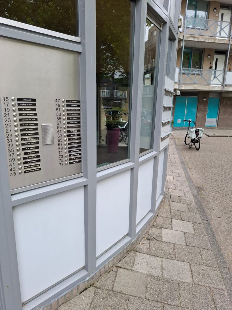 Appartementenbellenbord en fiets voor gebouw.