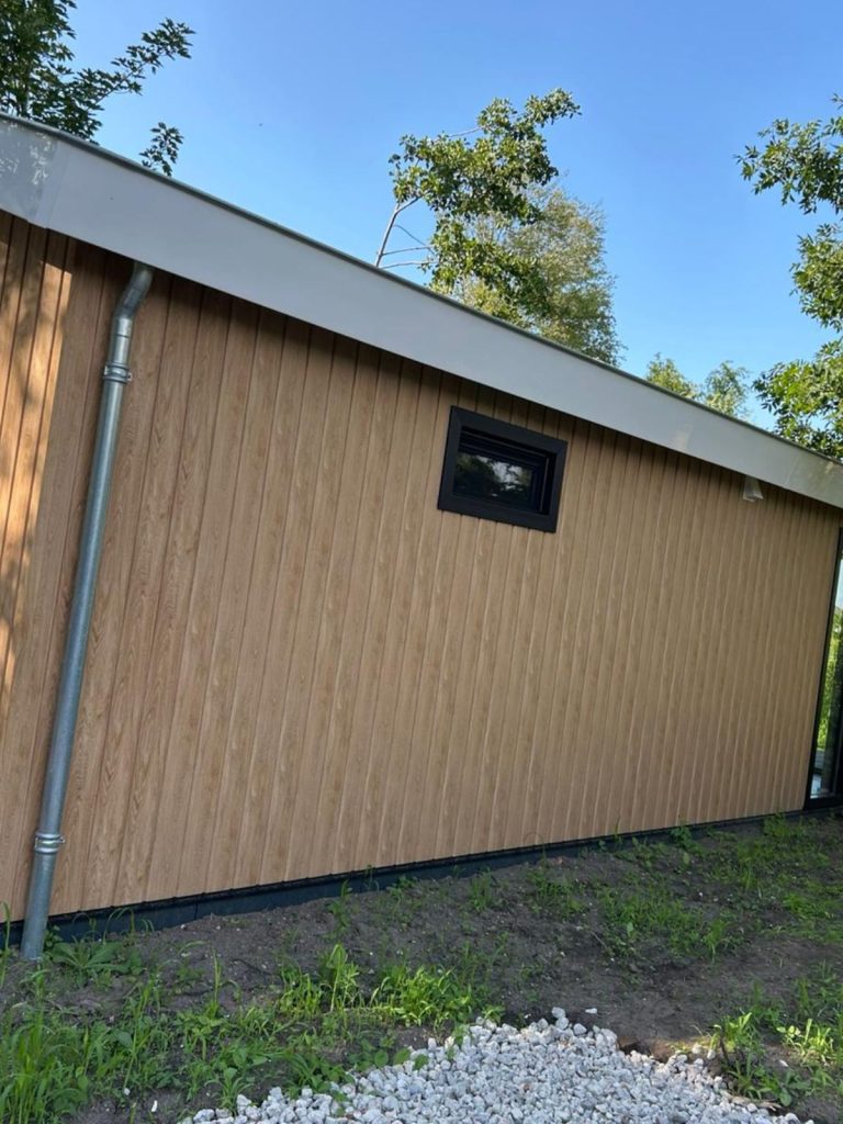 Houten wand van een huis met raam en regenpijp.